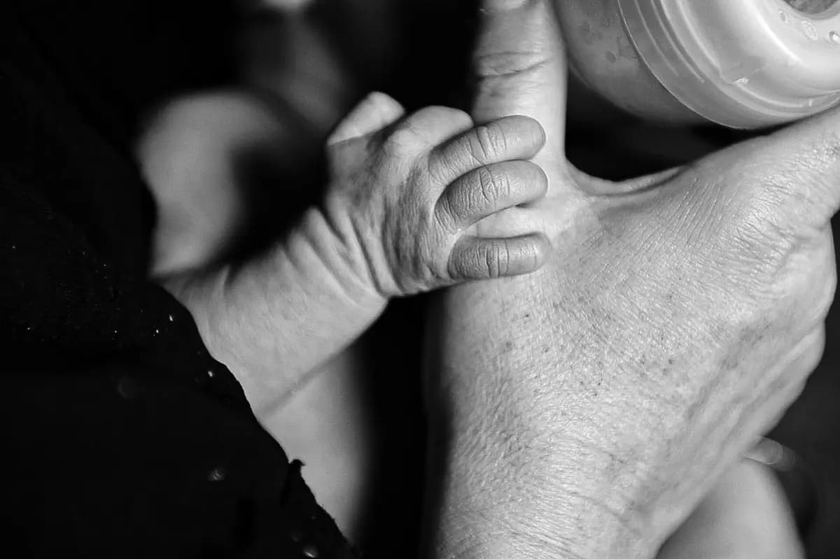 Main d’un bébé serrant la main d’un parent, en noir et blanc