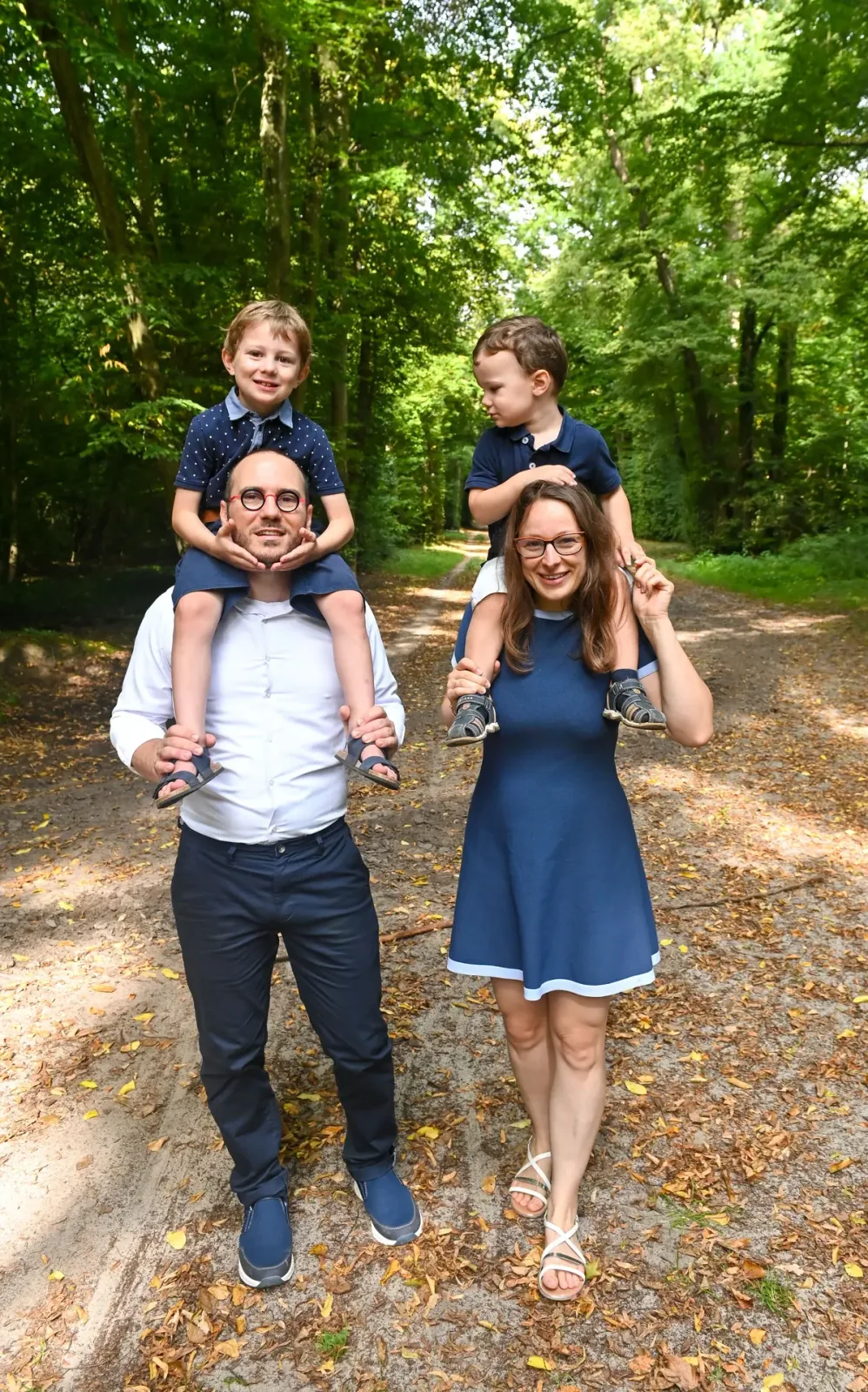 Parents portant leurs enfants sur les épaules en forêt
