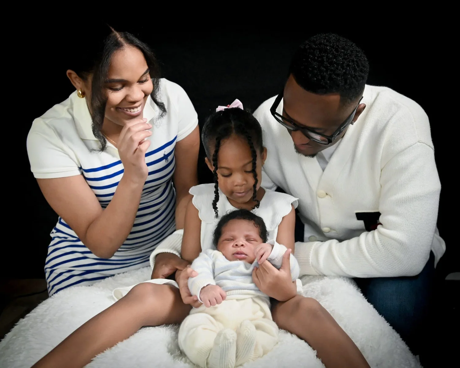 Parents, grande sœur et nouveau-né réunis lors d'une séance photo en studio