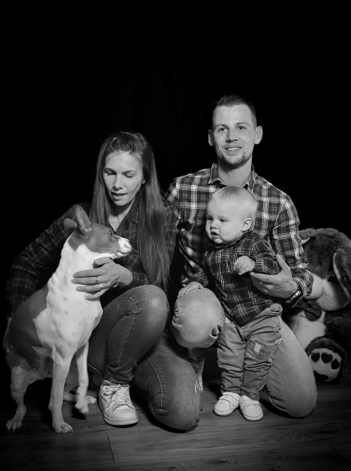 Parents, bébé et chien réunis en studio, photo de famille en noir et blanc