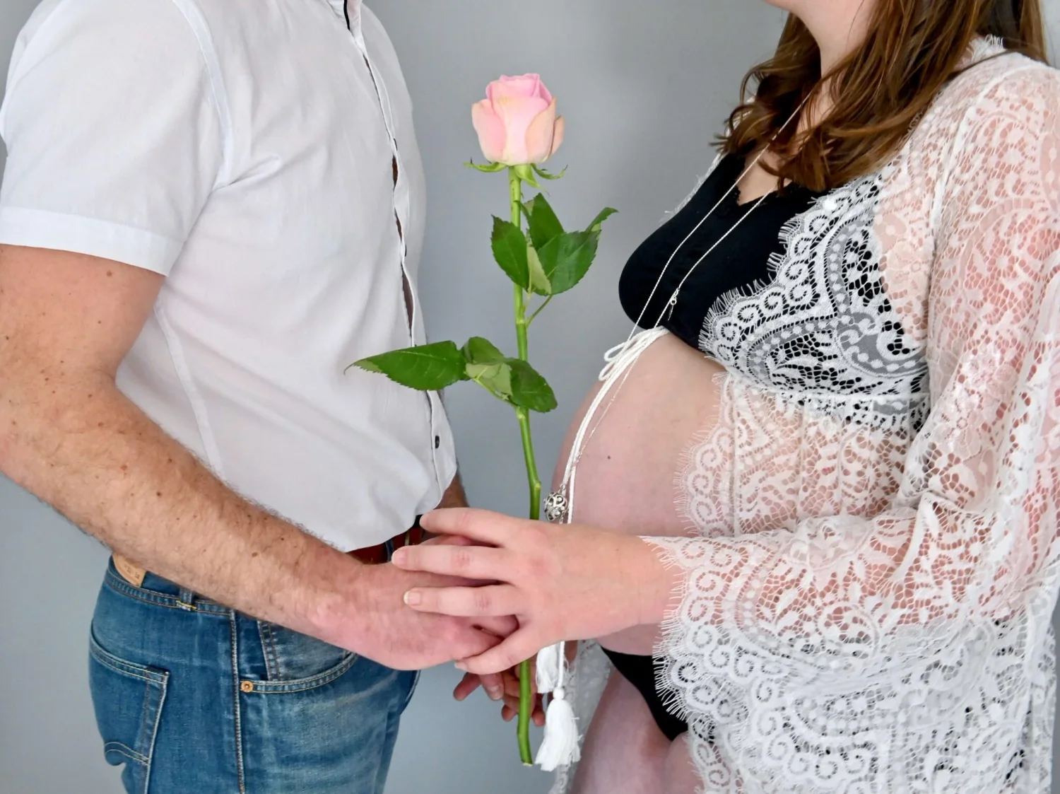 Couple tenant une rose devant le ventre arrondi de la future maman