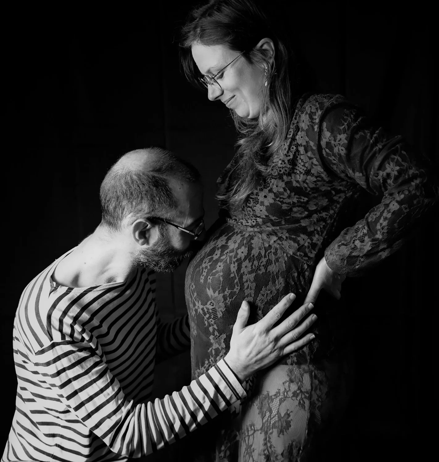 Futur papa embrassant le ventre de la future maman, en noir et blanc