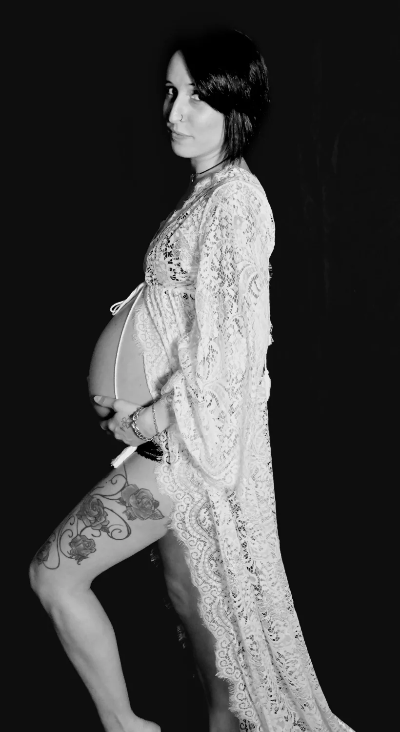 Future maman de profil en robe de dentelle, photo de grossesse en noir et blanc