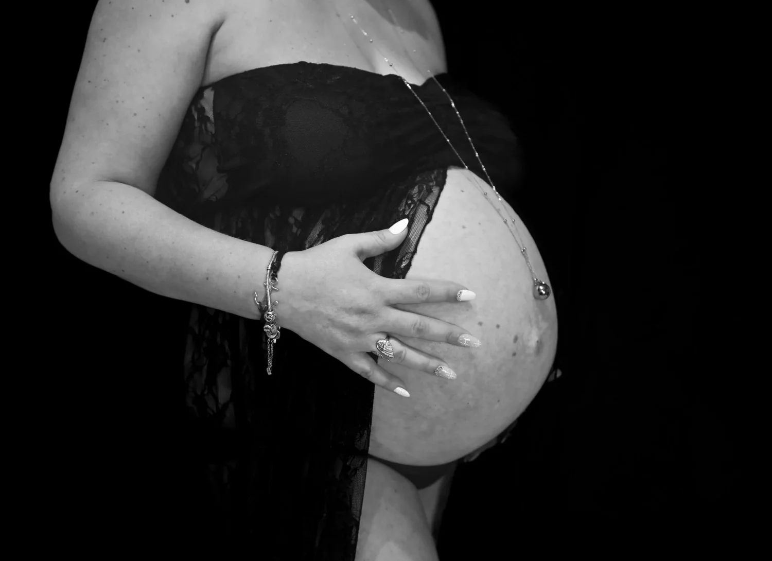 Mains sur le ventre arrondi d'une future maman, photo de grossesse en noir et blanc