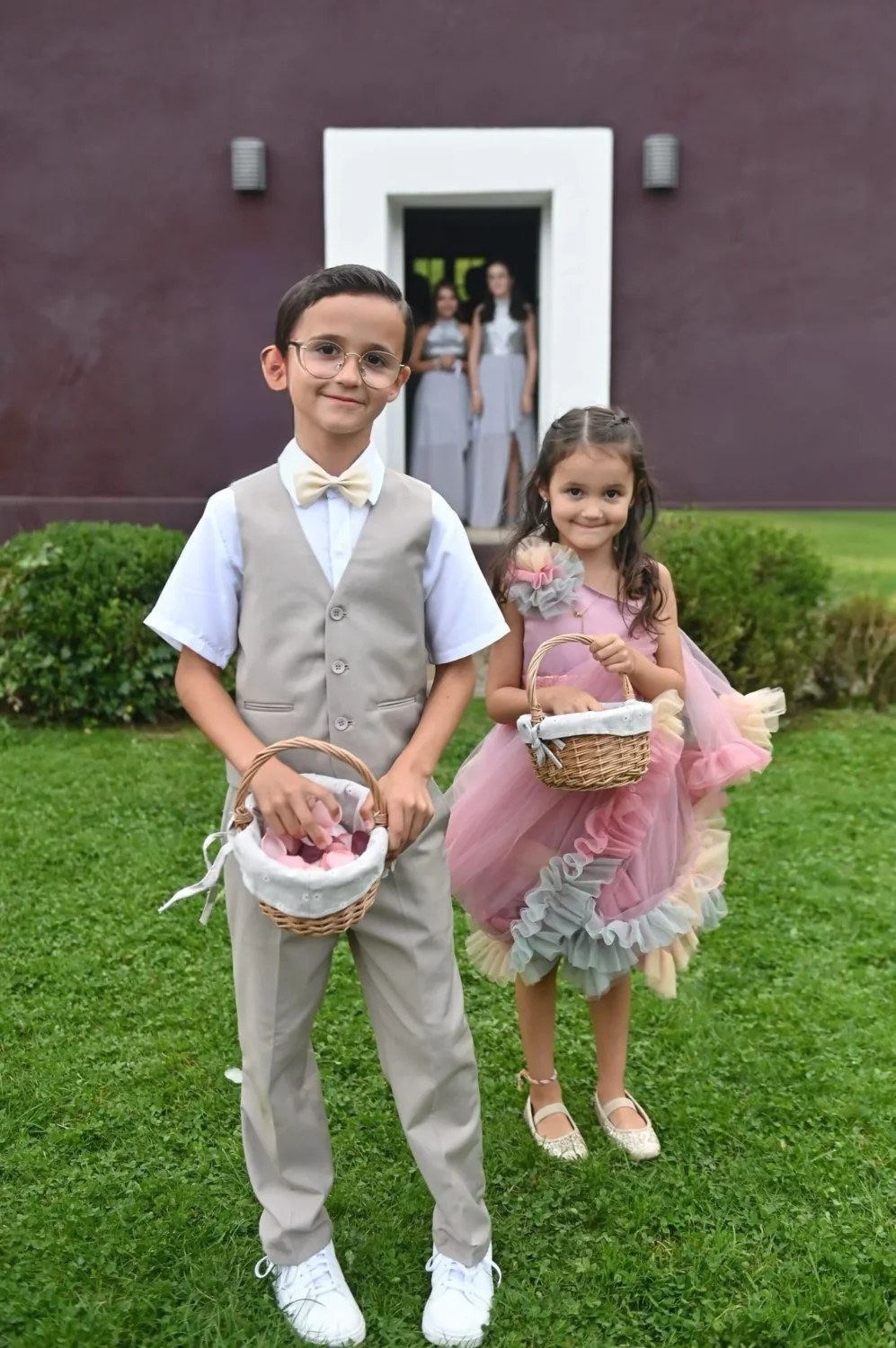 Garçon et fille d'honneur posant devant une maison