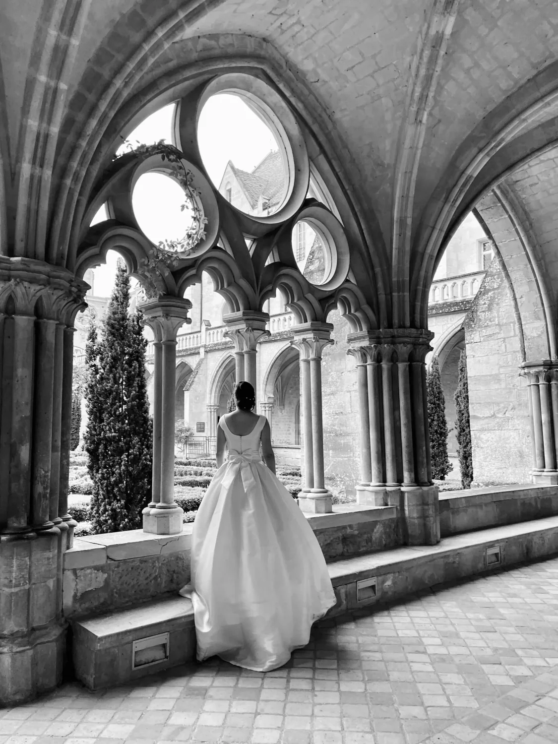 Mariée sous les arcades d'un cloître, photo de mariage en noir et blanc