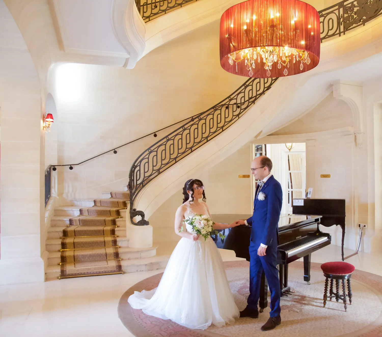 Mariés dans un hall avec escalier en colimaçon et piano à queue
