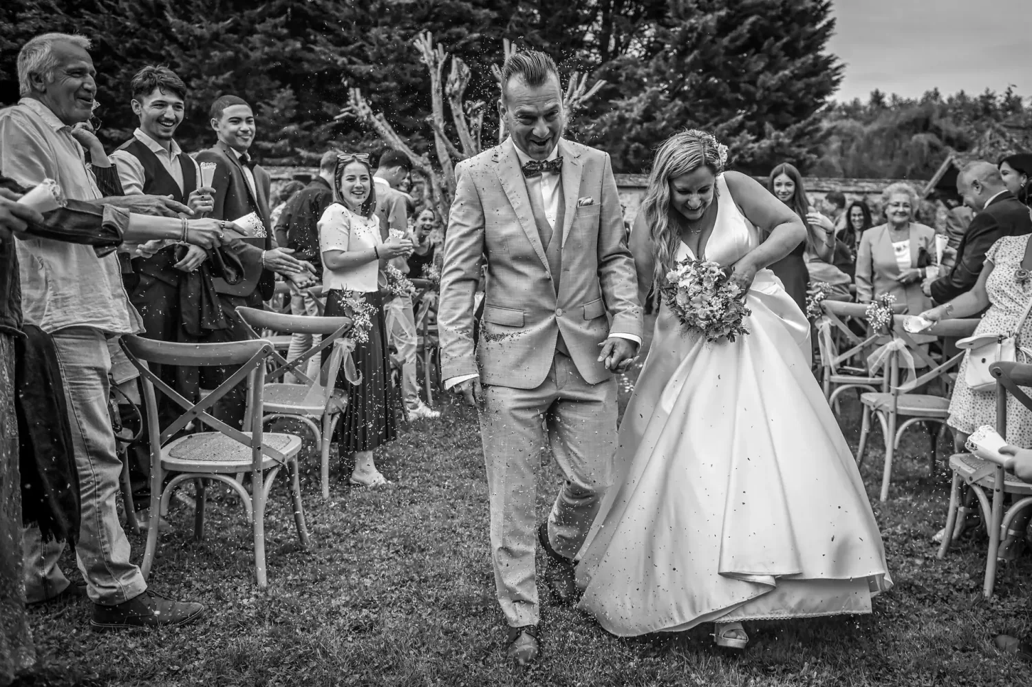 Sortie de cérémonie des mariés entre les invités, en noir et blanc