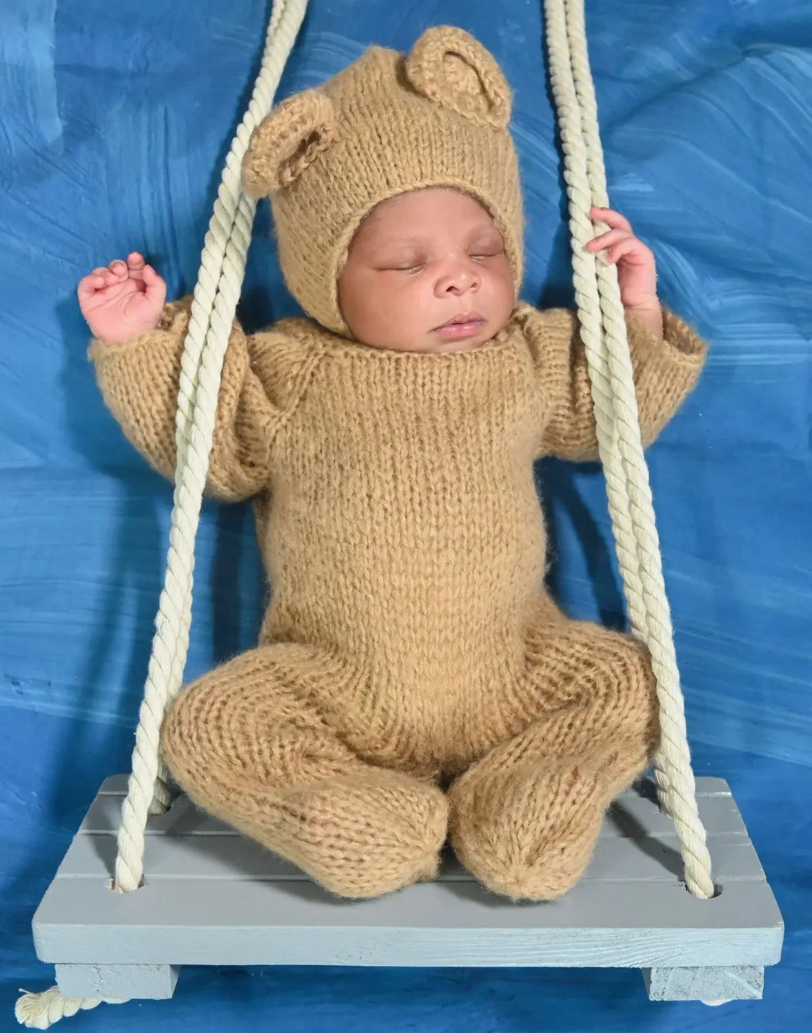 Nouveau-né en combinaison ourson installé sur une balançoire