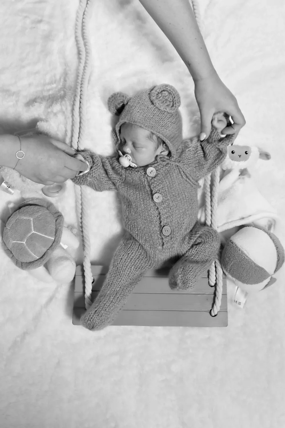 Nouveau-né en combinaison ourson vu du dessus, en noir et blanc