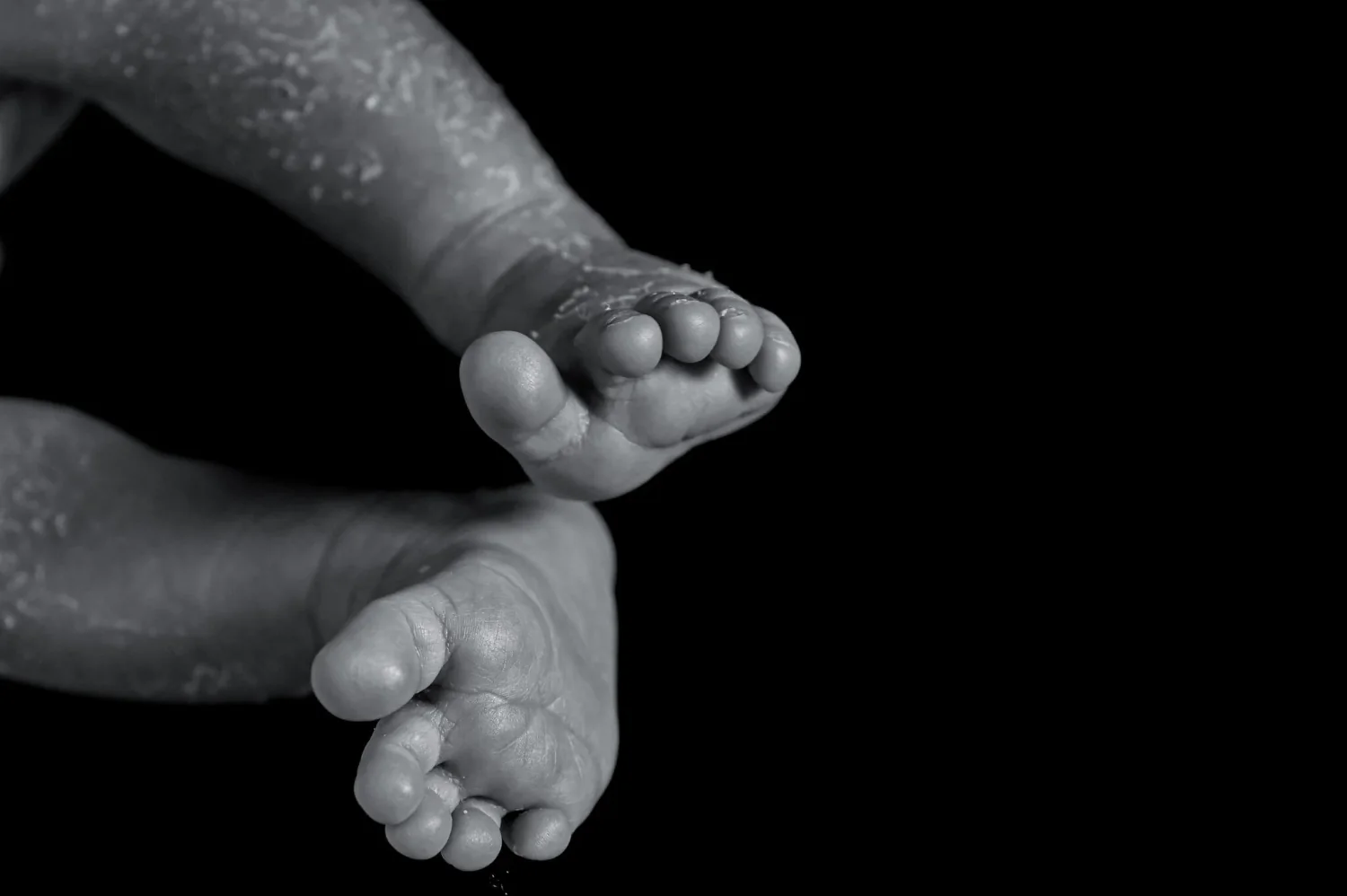 Pieds de nouveau-né dans les mains d'un parent sur fond noir