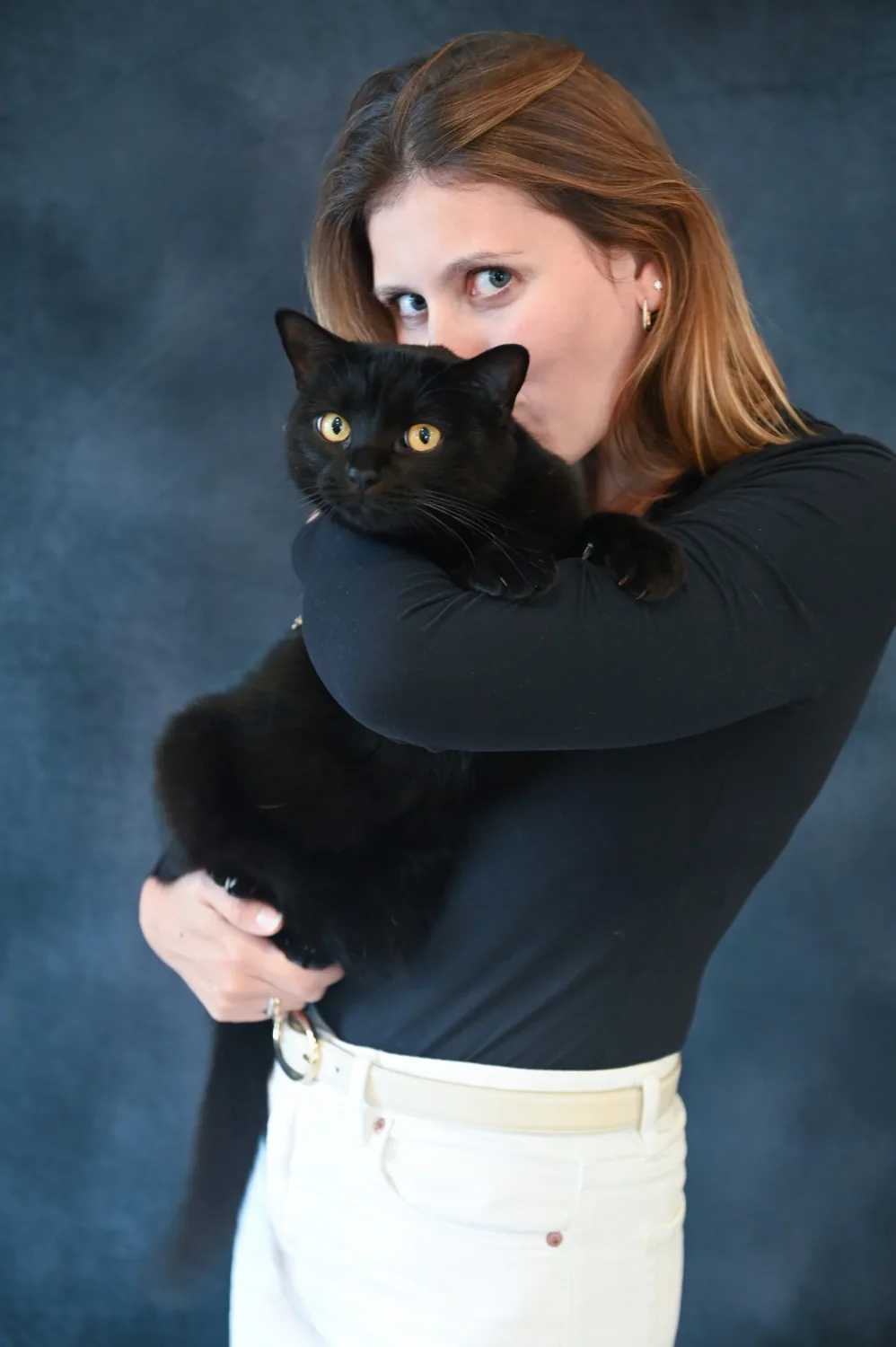 Portrait de femme tenant son chat noir contre elle, fond bleu