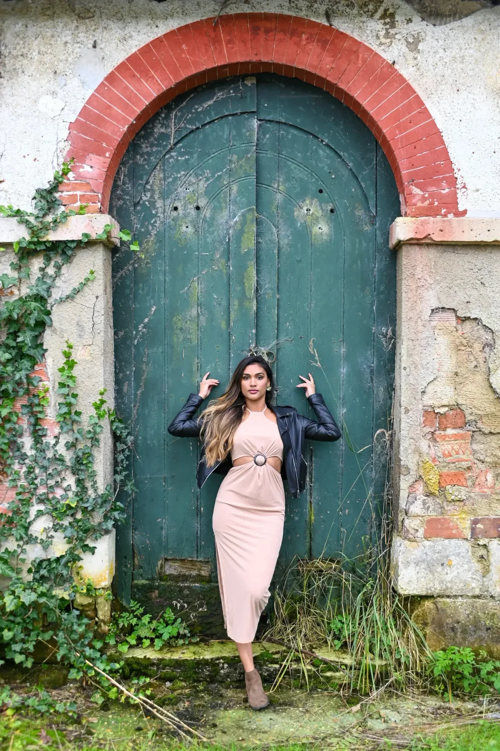Portrait de femme devant une ancienne porte verte en pierre