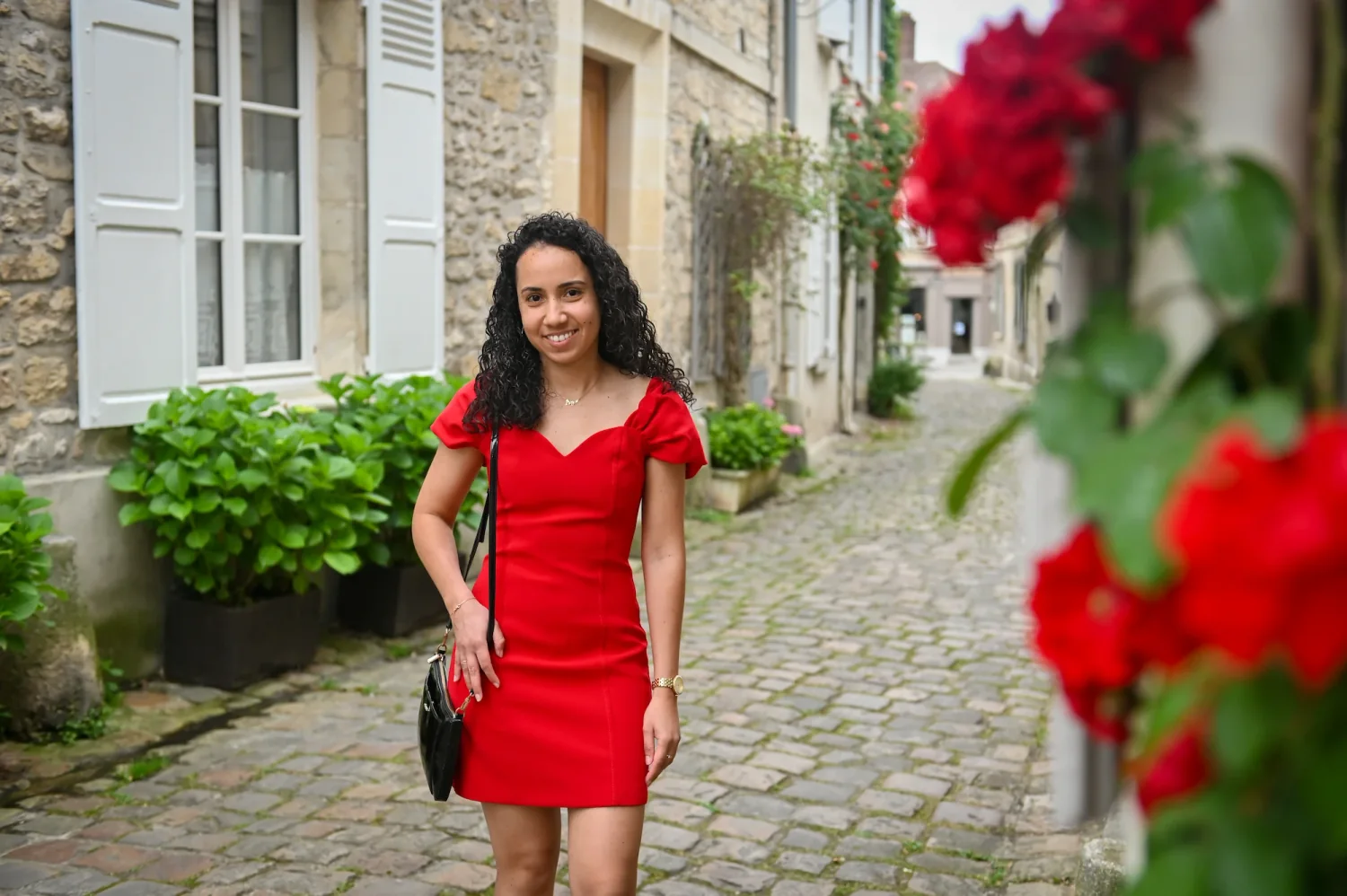 Portrait de femme en robe rouge dans une ruelle pavée