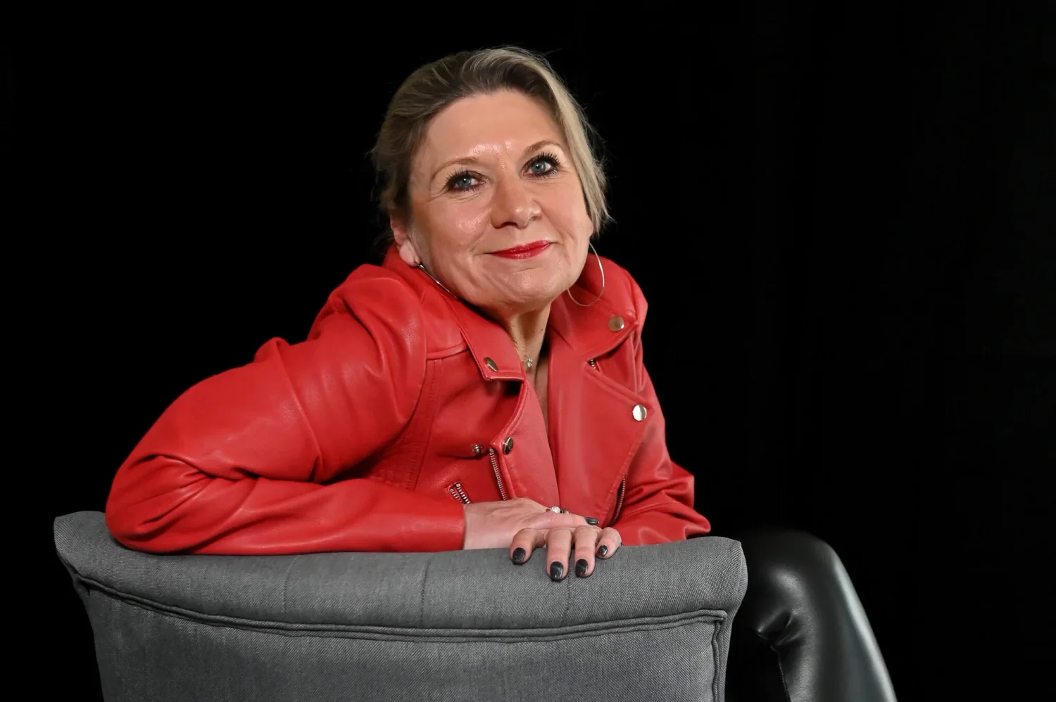 Portrait de femme en veste de cuir rouge accoudée à une chaise