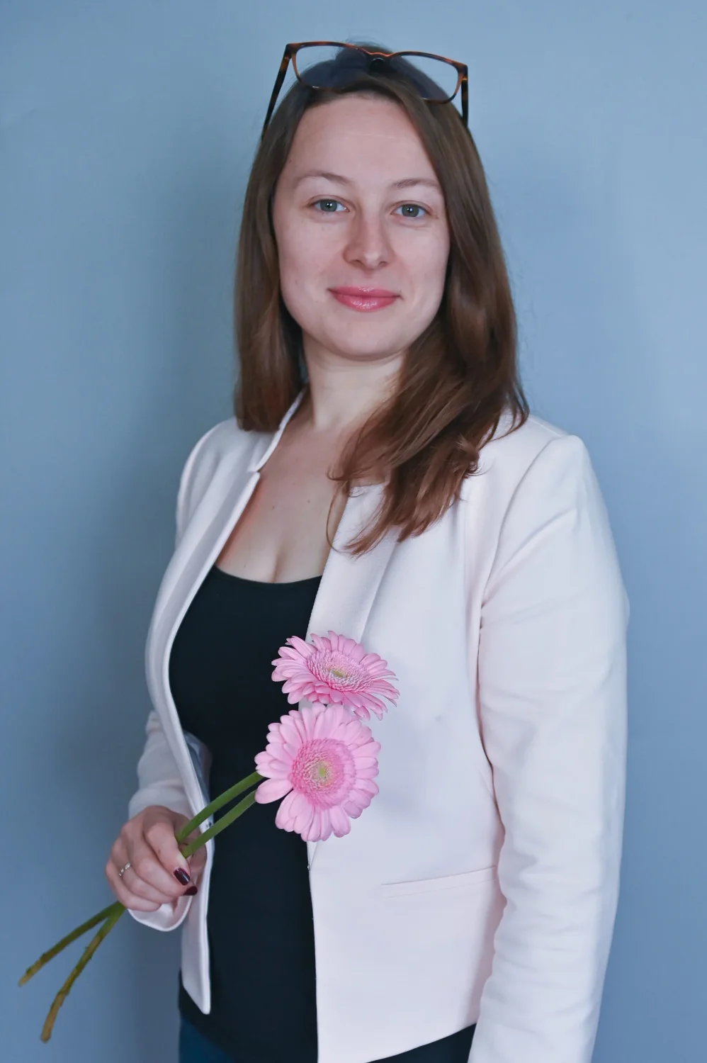 Portrait professionnel d'une femme en veste blanche tenant des fleurs roses