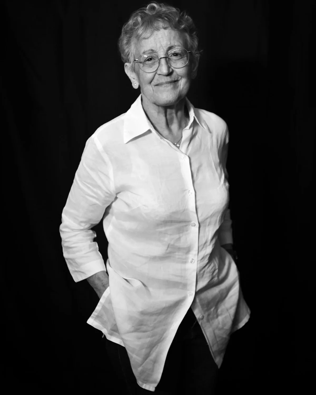 Portrait d'une femme âgée souriante en chemise blanche, en noir et blanc